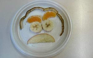 Faccia realizzata da un bambino con pezzi di frutta
