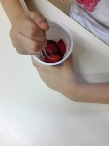 Le mani di un bambino che mangia frutta da un bicchiere
