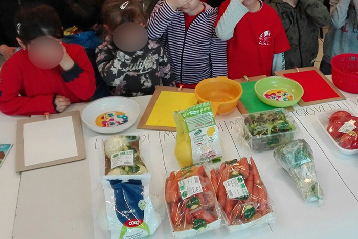 Bambini che osservano verdura divisa per giornate sul banco