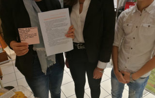 Persone che tengono in mano un foglio e dei consigli su come non inquinare