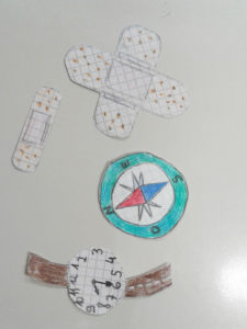 Ritagli di disegni fatti da un bambino di cerotti, orologio e bussola